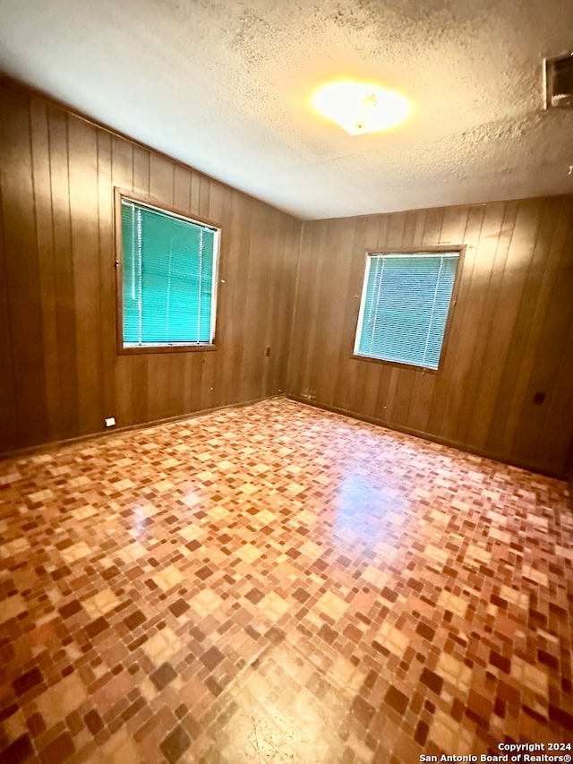 spare room featuring wood walls and a textured ceiling