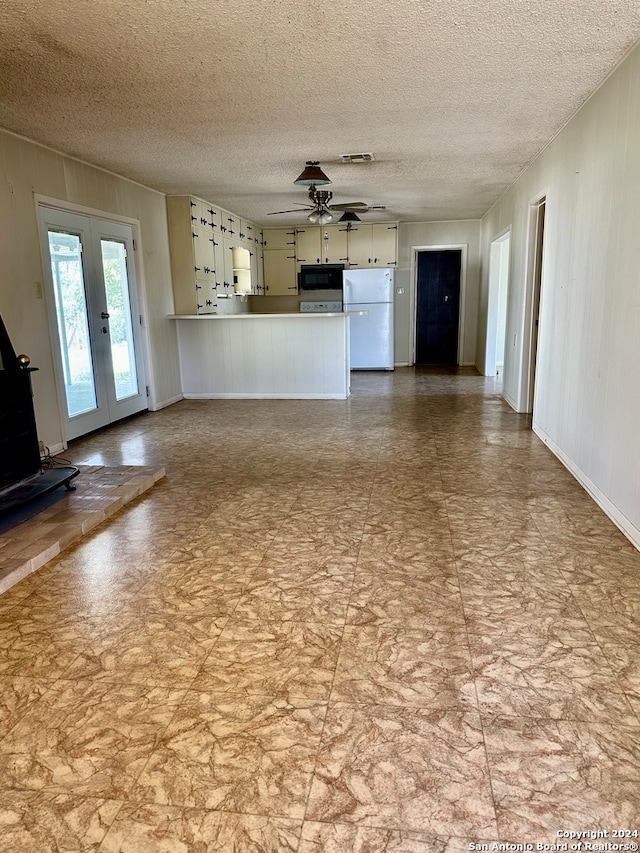 unfurnished living room with ceiling fan, a textured ceiling, and french doors