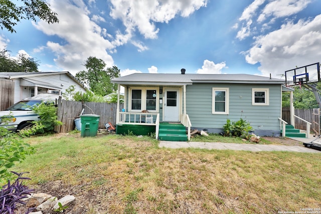 bungalow-style house featuring a front lawn and fence