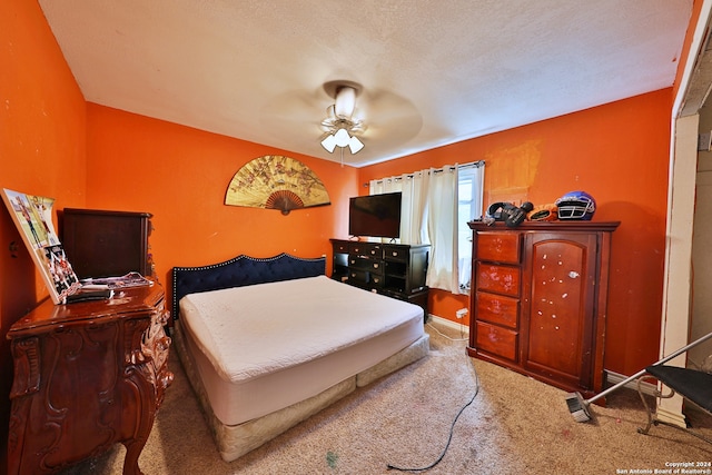 carpeted bedroom with ceiling fan and a textured ceiling