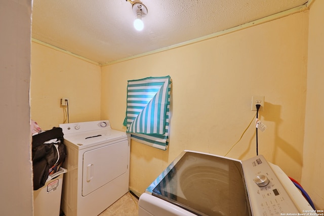 laundry area with light tile patterned floors, a textured ceiling, and separate washer and dryer