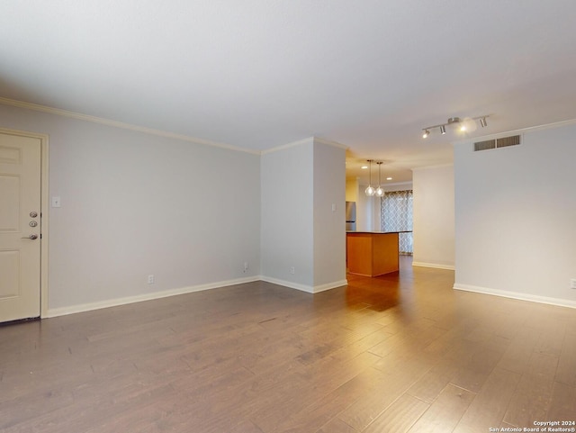 spare room with ornamental molding, wood-type flooring, rail lighting, and a chandelier