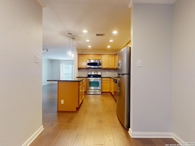 kitchen featuring backsplash, light wood-type flooring, appliances with stainless steel finishes, a kitchen breakfast bar, and pendant lighting