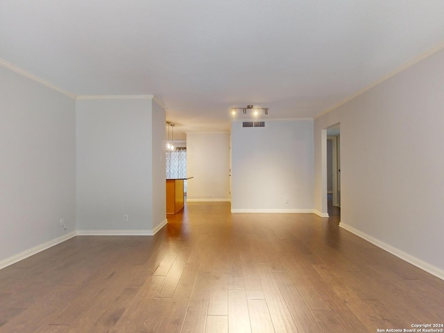 spare room with hardwood / wood-style floors, a notable chandelier, and ornamental molding