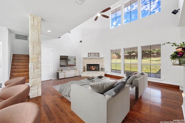 living room featuring a fireplace, a high ceiling, dark hardwood / wood-style flooring, and ceiling fan