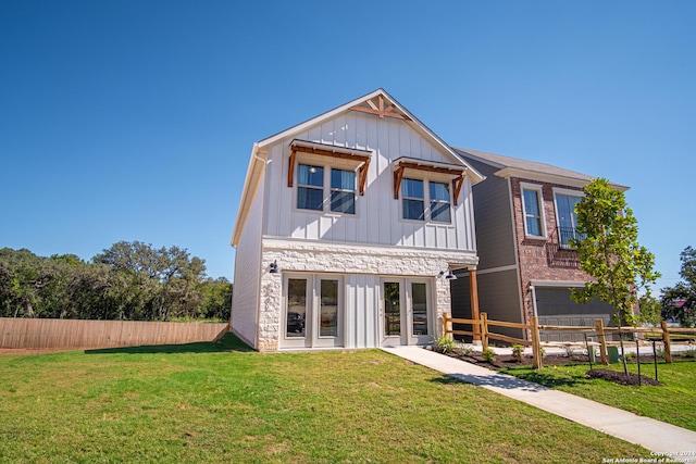 rear view of property featuring a yard, board and batten siding, french doors, and fence