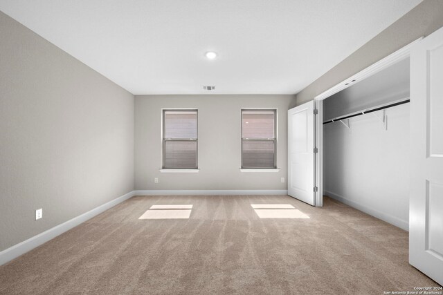 unfurnished bedroom with a closet and light colored carpet