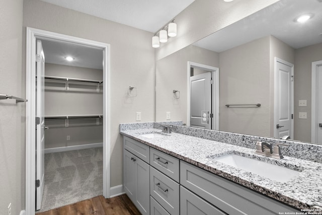 bathroom with double vanity, wood finished floors, baseboards, and a sink