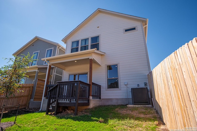 rear view of property featuring a yard, covered porch, central AC unit, and fence