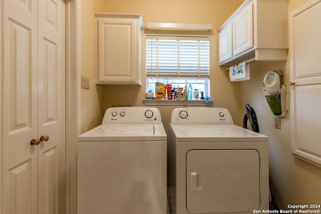 clothes washing area with cabinets and separate washer and dryer