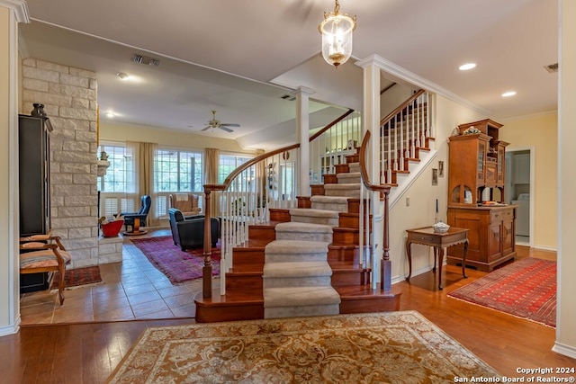 stairway featuring washer / clothes dryer, ceiling fan, ornamental molding, and wood-type flooring