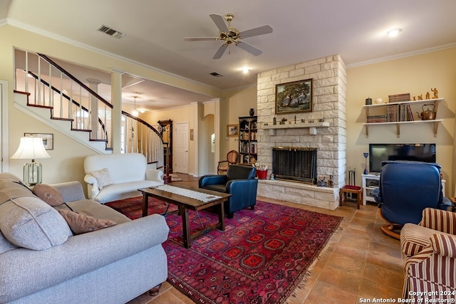 living room featuring ceiling fan, ornamental molding, and a stone fireplace