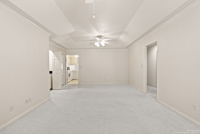 unfurnished room featuring a raised ceiling, ceiling fan, ornamental molding, and light carpet