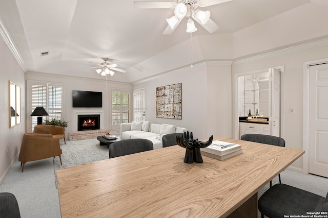 dining room with a fireplace, plenty of natural light, a tray ceiling, and ceiling fan