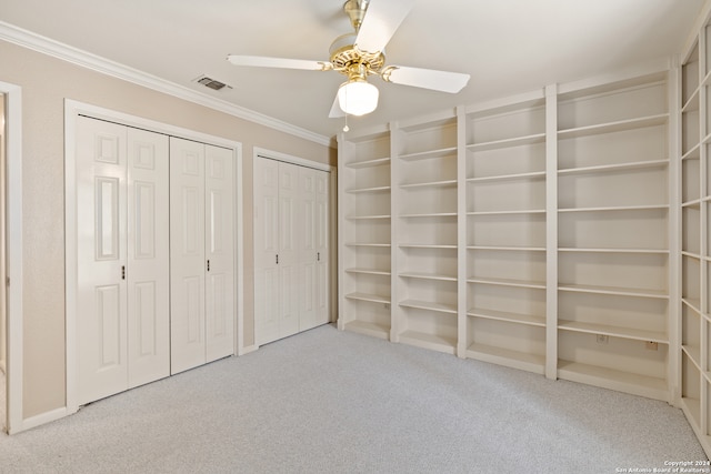 unfurnished bedroom with two closets, ceiling fan, crown molding, and carpet floors