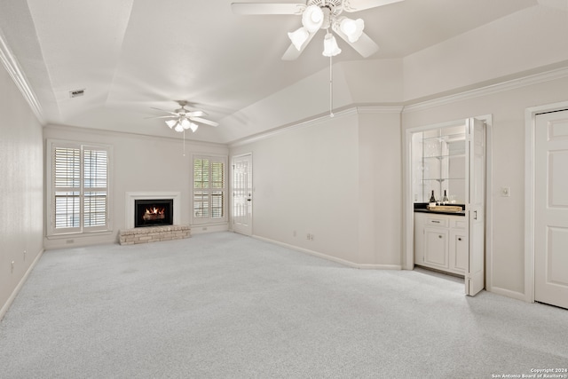 unfurnished living room with a fireplace, crown molding, light carpet, a tray ceiling, and ceiling fan