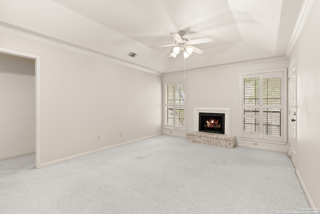 unfurnished living room with a brick fireplace, light colored carpet, a raised ceiling, ceiling fan, and ornamental molding