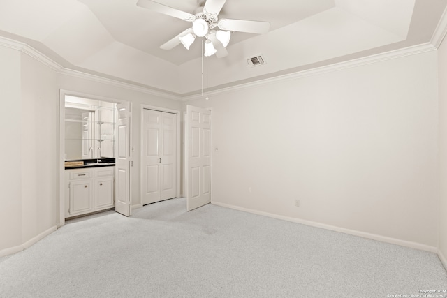 unfurnished bedroom featuring light colored carpet, a raised ceiling, crown molding, and ceiling fan