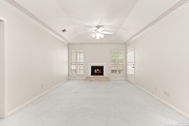 unfurnished living room with ceiling fan, light colored carpet, crown molding, and a brick fireplace