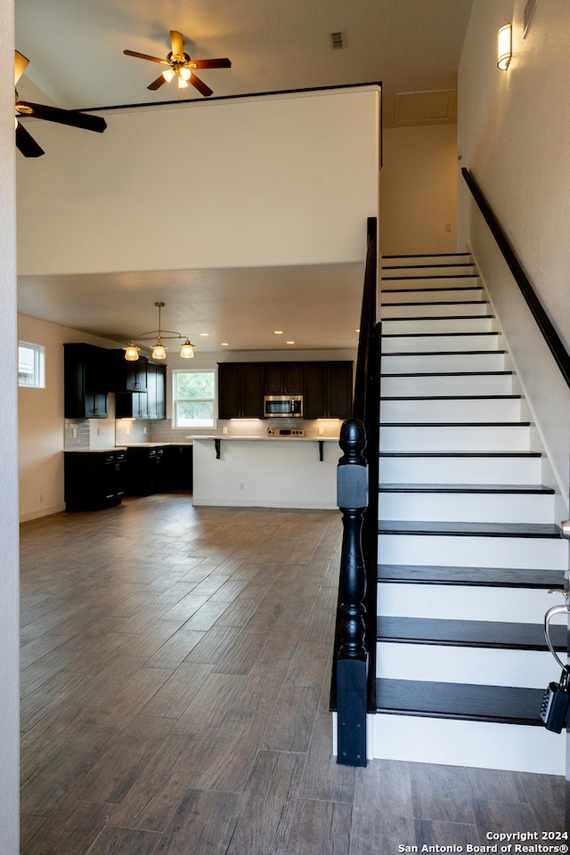 stairs with ceiling fan and hardwood / wood-style flooring