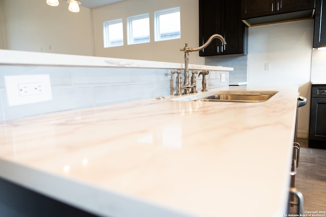 kitchen featuring tasteful backsplash, wood-type flooring, light stone counters, and sink