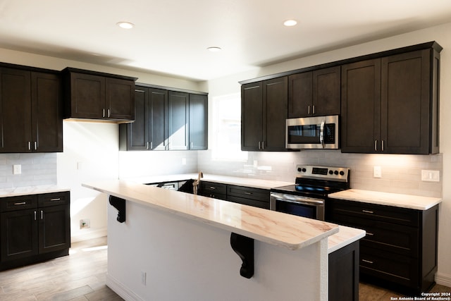 kitchen featuring appliances with stainless steel finishes, decorative backsplash, and light hardwood / wood-style floors