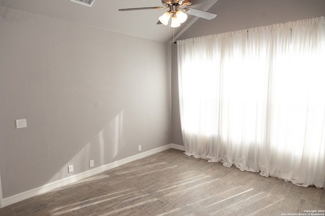 empty room with vaulted ceiling, ceiling fan, and light hardwood / wood-style floors