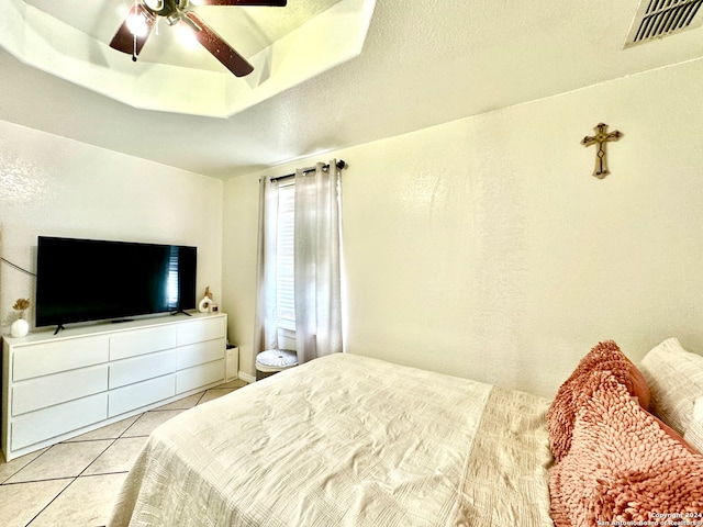 tiled bedroom with a textured ceiling, a raised ceiling, and ceiling fan