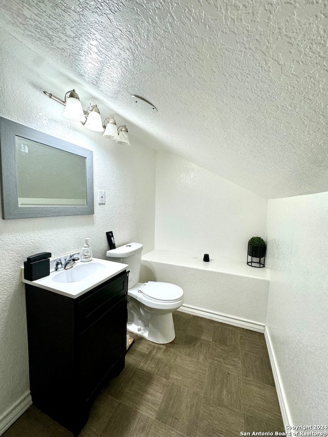 bathroom featuring a bathtub, toilet, a textured ceiling, and vanity