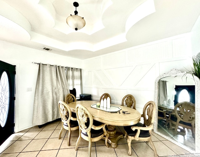 dining room featuring a raised ceiling and light tile patterned floors