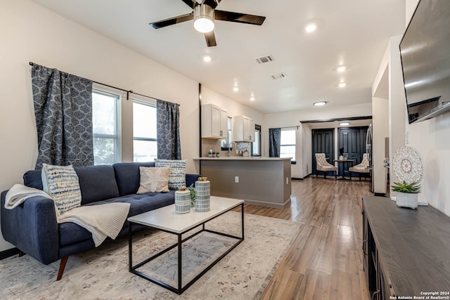 living room with ceiling fan and light hardwood / wood-style flooring