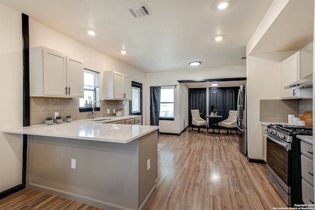 kitchen with appliances with stainless steel finishes, white cabinetry, plenty of natural light, and light hardwood / wood-style flooring