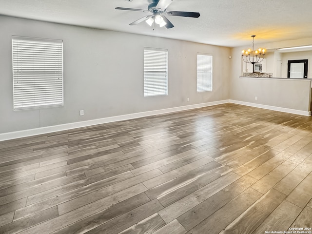 spare room with ceiling fan with notable chandelier, wood-type flooring, and a textured ceiling