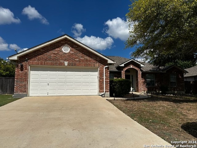 ranch-style home featuring brick siding, an attached garage, driveway, and fence