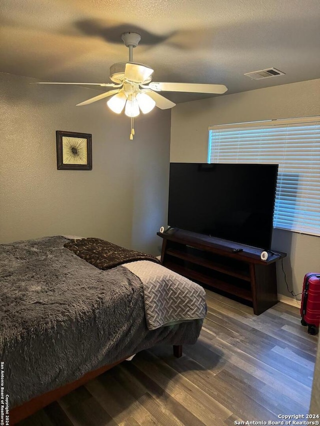 bedroom featuring a textured ceiling, ceiling fan, and wood-type flooring