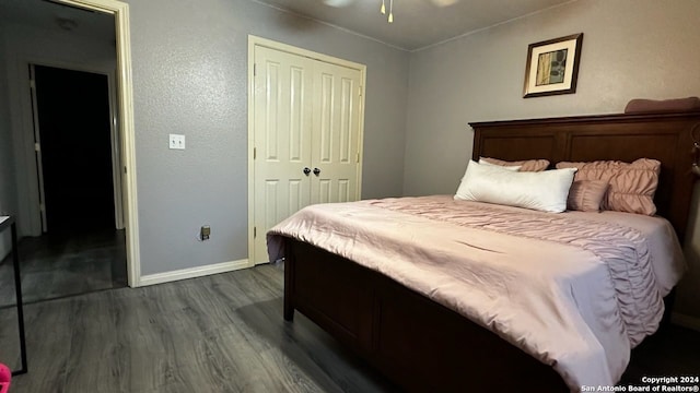 bedroom with dark wood-style floors, baseboards, a closet, and a textured wall