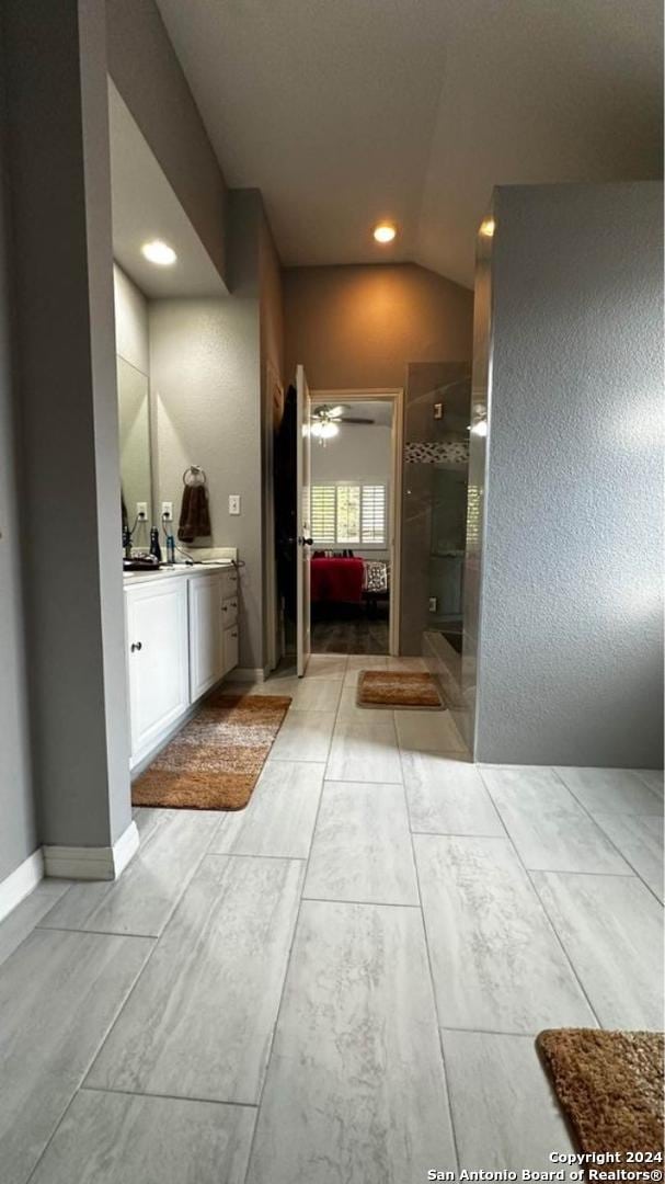 bathroom with connected bathroom, vaulted ceiling, recessed lighting, a stall shower, and vanity