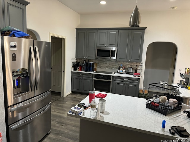 kitchen featuring gray cabinetry, backsplash, light stone counters, stainless steel appliances, and dark hardwood / wood-style floors