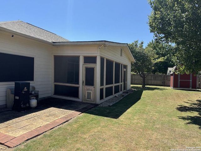 exterior space with an outbuilding, a sunroom, fence, and a shed