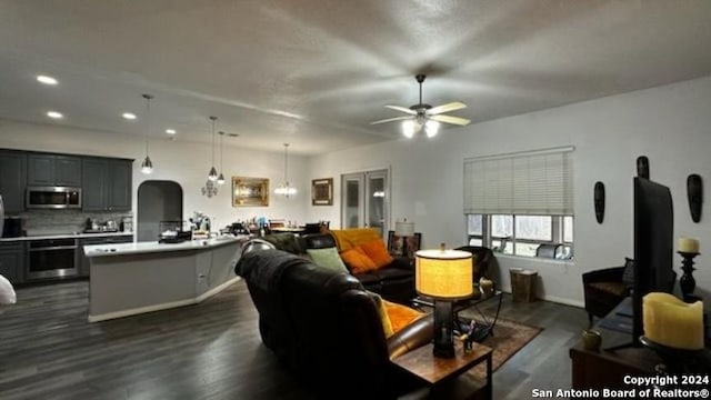 living area with arched walkways, recessed lighting, dark wood-type flooring, and ceiling fan