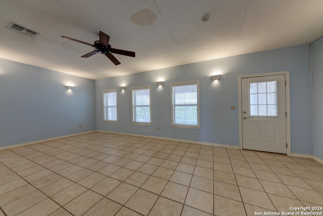 foyer featuring ceiling fan, light tile patterned flooring, and a textured ceiling