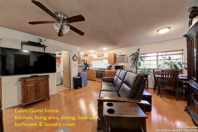 living room featuring light wood-type flooring, a textured ceiling, a wall mounted AC, and ceiling fan