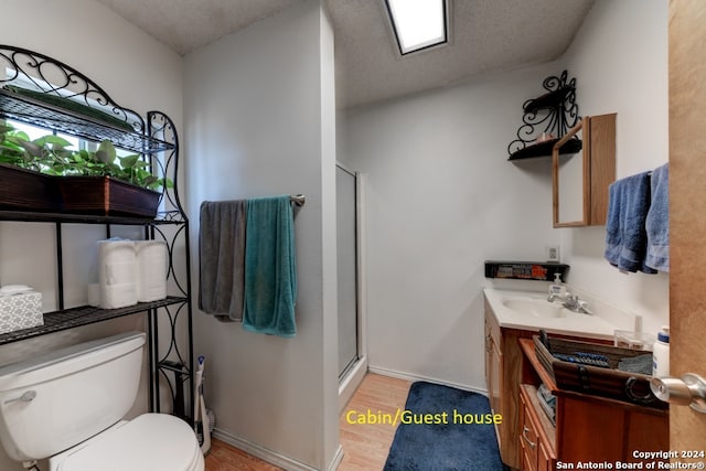 bathroom featuring vanity, a textured ceiling, wood-type flooring, toilet, and an enclosed shower