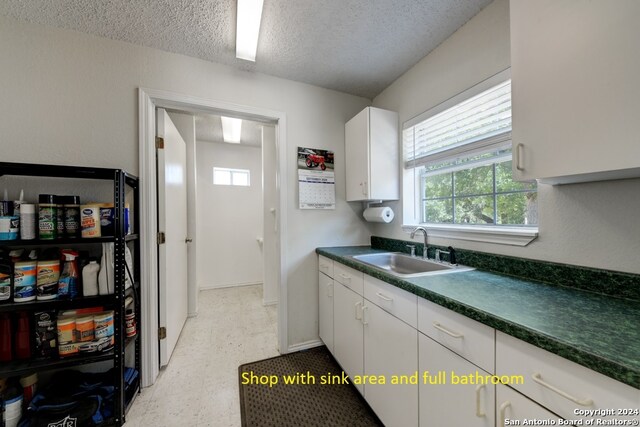 kitchen featuring a textured ceiling, white cabinetry, and sink