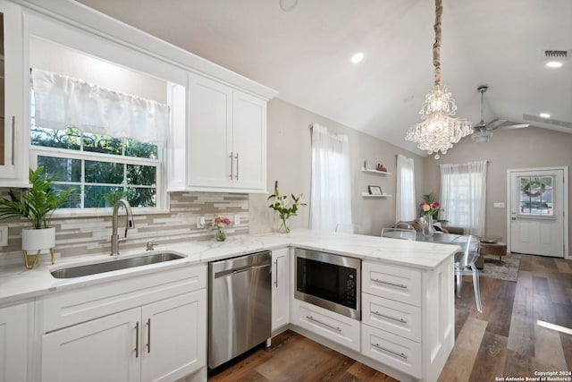 kitchen with kitchen peninsula, sink, built in microwave, vaulted ceiling, and stainless steel dishwasher