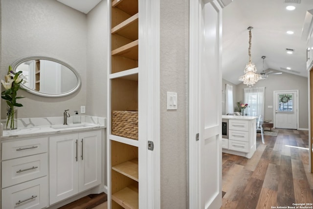 bathroom with vanity, vaulted ceiling, an inviting chandelier, and hardwood / wood-style floors