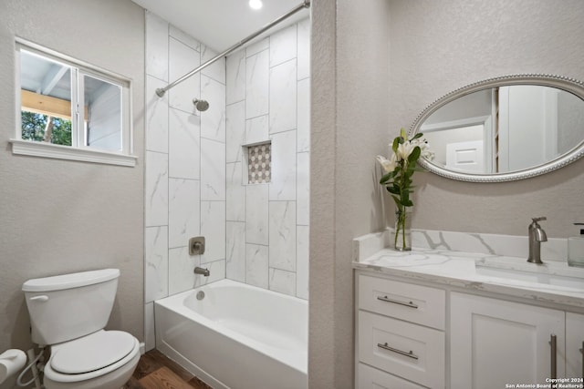 full bathroom featuring wood-type flooring, toilet, tiled shower / bath combo, and vanity