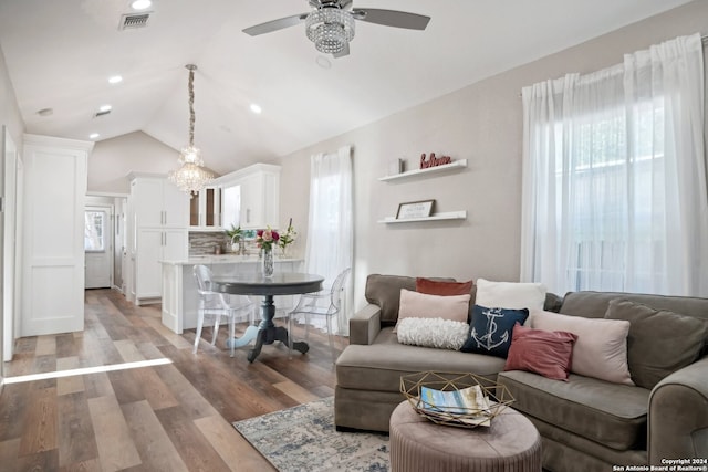 living room featuring ceiling fan with notable chandelier, vaulted ceiling, and light hardwood / wood-style flooring