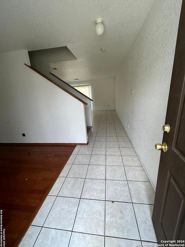 hallway with light wood-type flooring and a textured ceiling