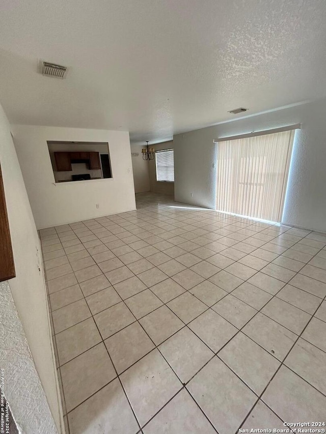 unfurnished living room featuring a textured ceiling and light tile patterned floors